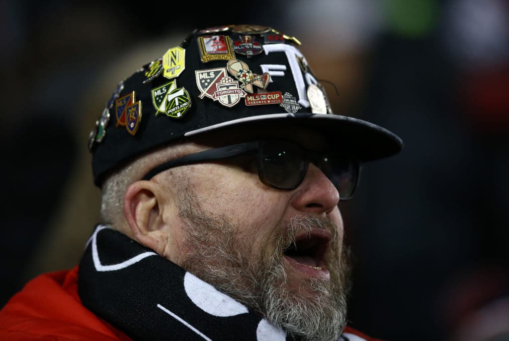 Un fan del Toronto porta una gorra llamativa con pins de diferentes equipos de nuestro soccer.