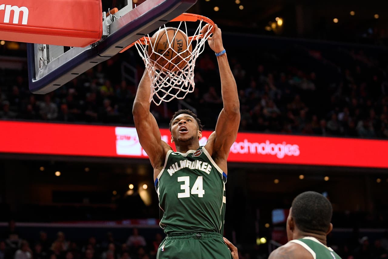 El delantero de los Milwaukee Bucks, Giannis Antetokounmpo, se cuelga de la canasta luego de clavar el balón con toda su furia en la victoria de los Bucks 137-134 sobre los Wizards.