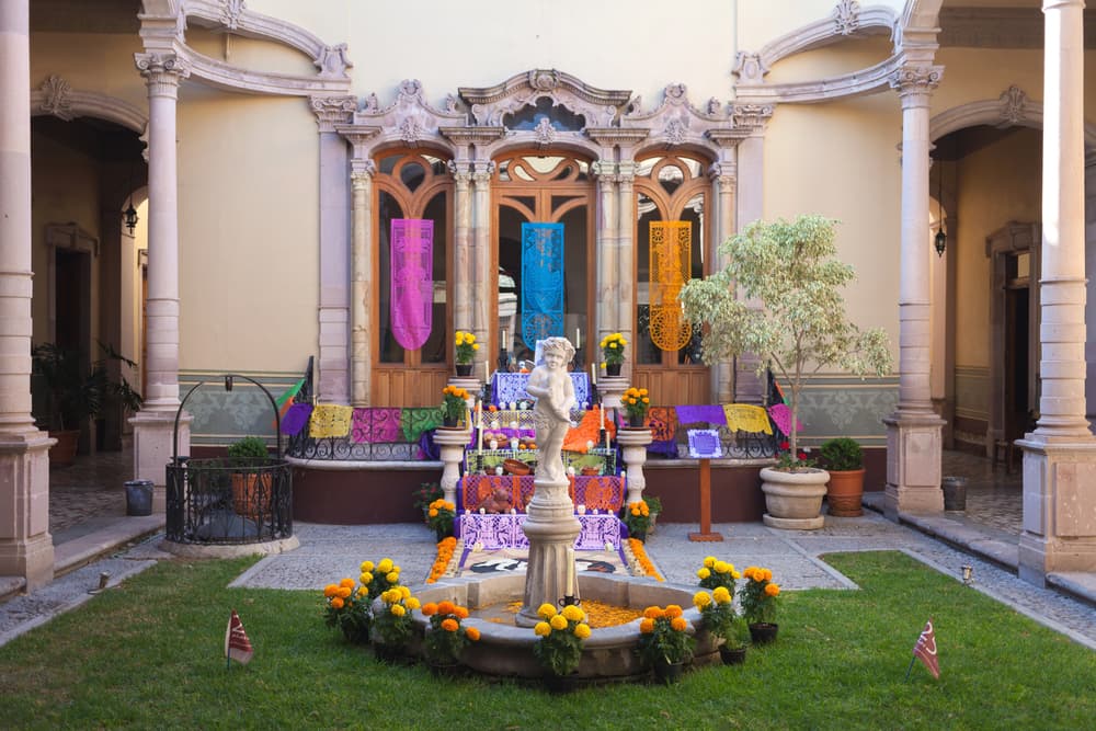 El altar de muertos es el centro de esta celebración y sus elementos vienen de la mezcla de tradiciones prehispánicas y católicas que se funden para celebrar la muerte. Por ejemplo, dentro de la visión prehispánica el acto de morir era el comienzo de un viaje de cuatro días hacia el Mictlán, el reino de los muertos descarnados o inframundo.
