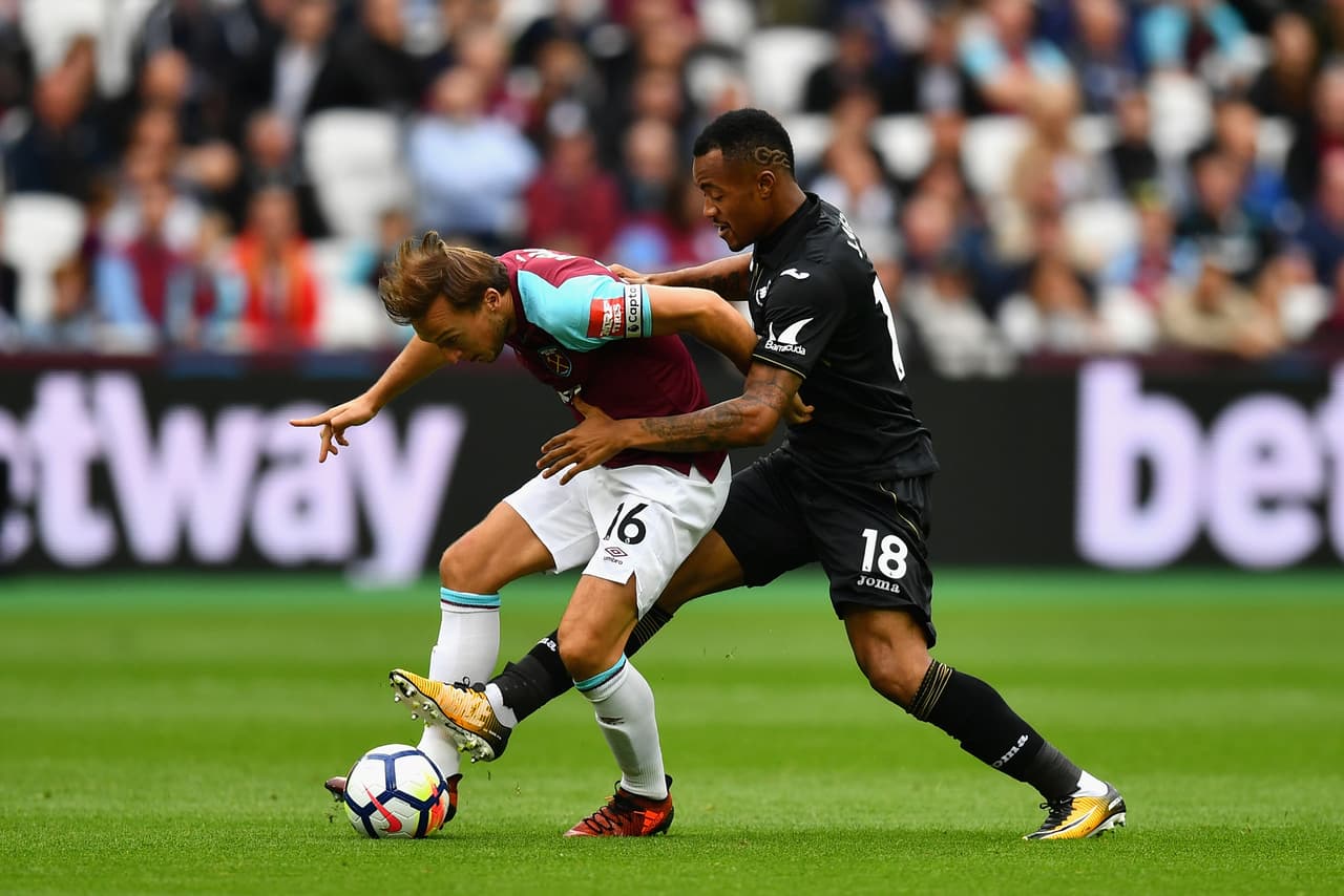 Mark Noble y Jordan Ayew, que enfrentaba a su hermano Andre Ayew, en un duelo por el balón.