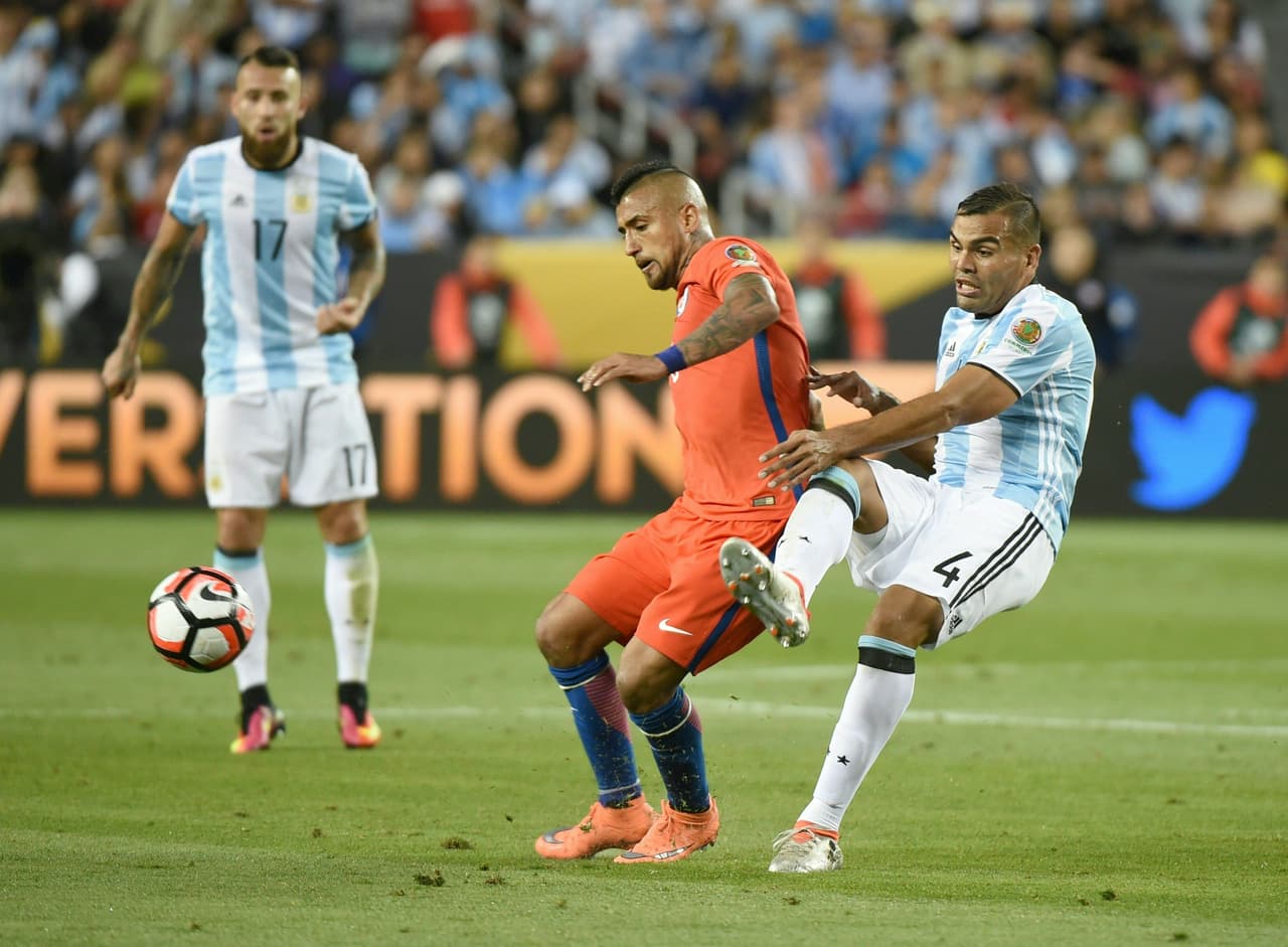 Arturo Vidal de Chile compite por el balón con el argentino Gabriel Mercado.