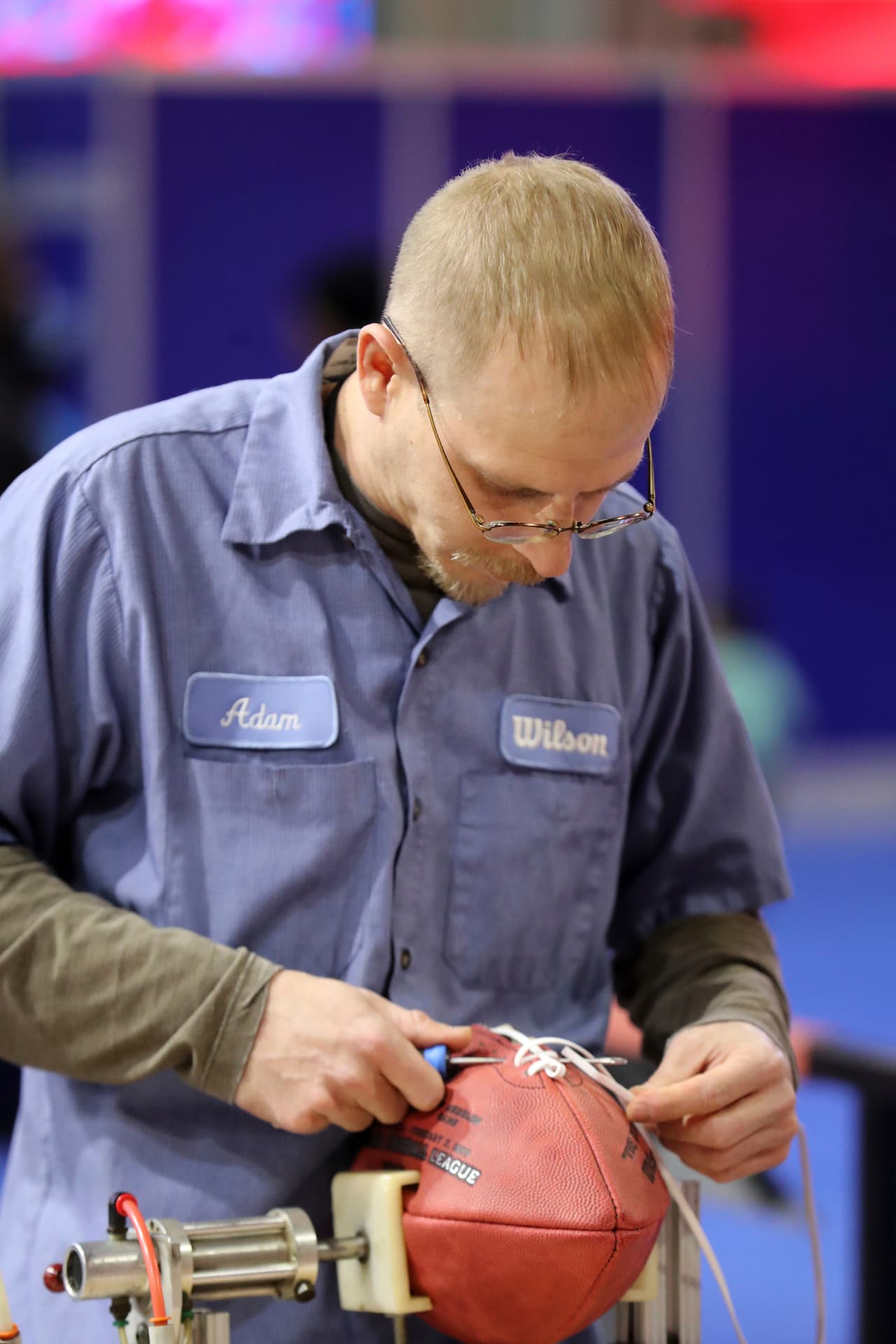Uno de los empleados de la marca Wilson, la oficial de los balones con los que se juegan en la NFL y el Super Bowl, muestra cómo se atan las cuerdas a un ovoide.