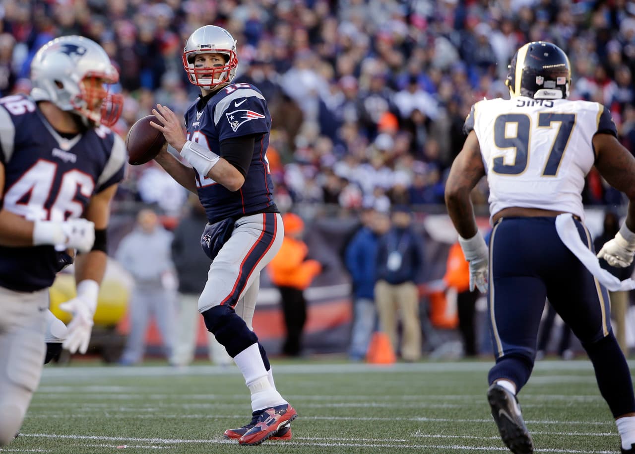 New England Patriots quarterback Tom Brady (12) looks for a receiver as Los Angeles Rams defensive end Eugene Sims (97) chases during the first half of an NFL football game, Sunday, Dec. 4, 2016, in Foxborough, Mass. (AP Photo/Elise Amendola)