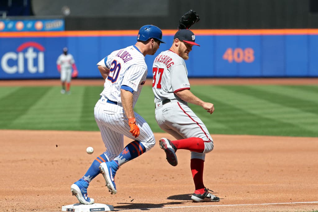 Pete Alonso trata de llegar quito a primera base ante la asistencia de Stephen Strasburg. Alonso se ponchó dos veces ante los lanzamientos del abridor de Washington.