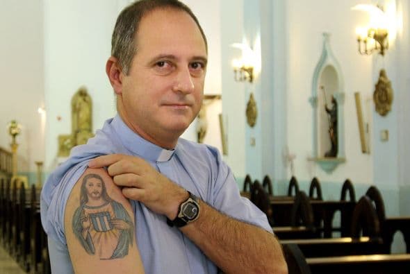 El Párroco Juan Gabriel Arias muestra un tatuaje que representa una imagen de Cristo que sostiene el escudo de fútbol del Racing. El sacerdote se convirtió en miembro del comité ejecutivo del Racing después de recibir la autorización del cardenal Jorge Bergoglio ahora Papa Francisco.
