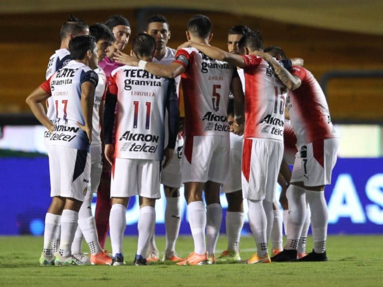 Jugadores de Chivas se reúnen en medio campo antes de un partido.