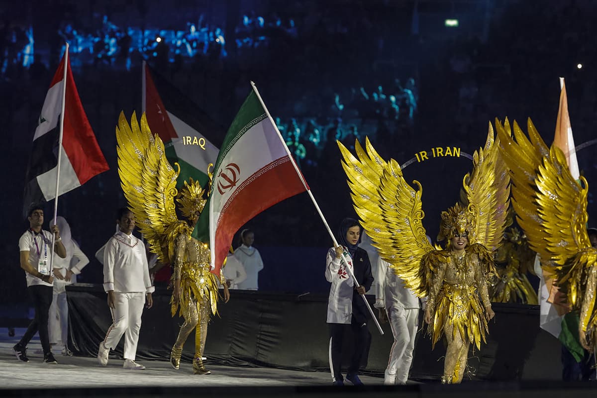Las delegaciones de Irán e Irak acompañadas por edecanes con vistosos trajes en la ceremonia de clausura.