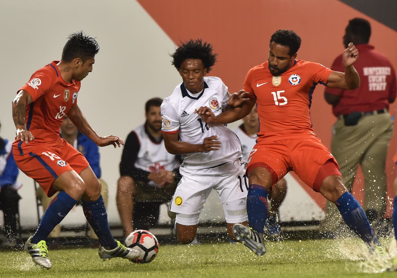 Ahora el agua es también protagonista, Juan Cuadrado de Colombia lucha por el balón con los chilenos Gonzalo Jara y Jean Beausejour.