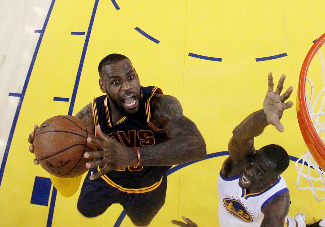 Lebron James de los Cleveland Cavaliers intenta clavar el balón en la canasta ante la marca de Green de los Golden State Warriors en uno de los seis partidos de la Final de la NBA 2015.