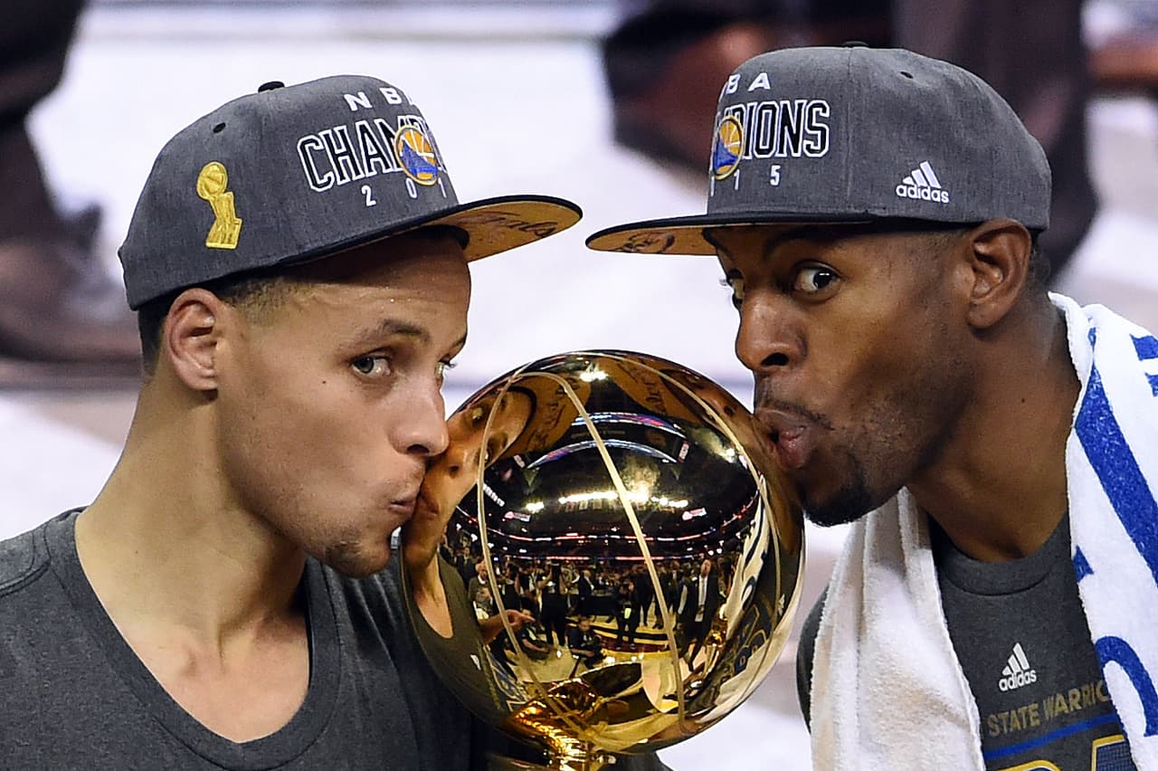 Stephen Curry y Andre Igoudala besan el trofeo de Larry O'brien que los distingue como campeones de la NBA. En esta final los Golden State Warriors se impusieron en seis juegos a los Cleveland Cavaliers.