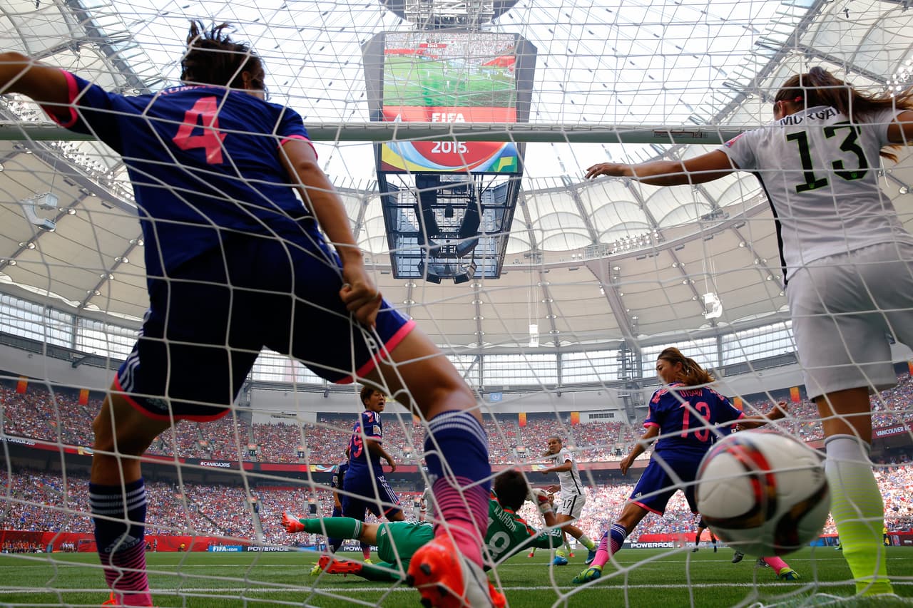 Una defensa de la selección femenil de Japón intenta sacar el balón de su portería en un remate de Heath, jugadora de Estados Unidos.