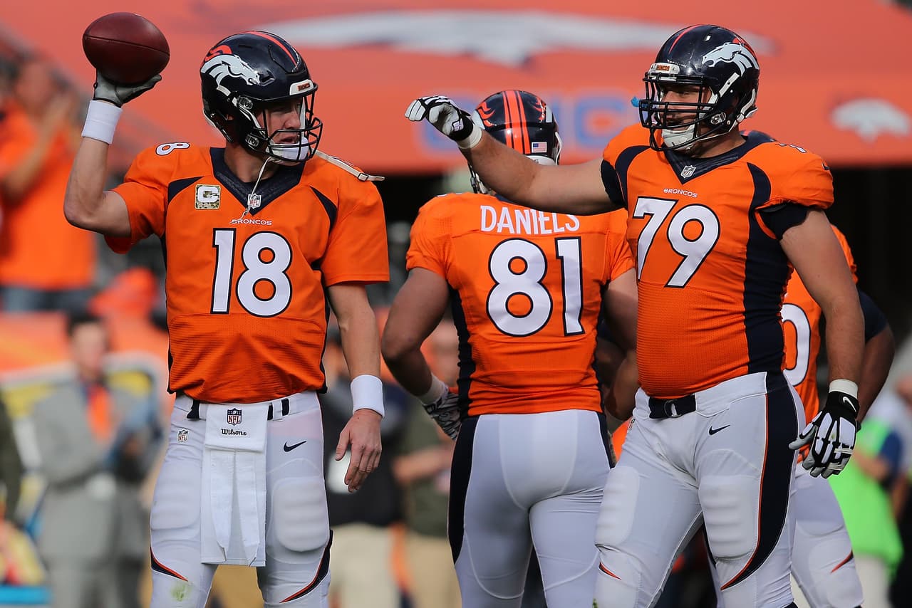 Peyton Manning, mariscal de campo de los Denver Broncos, sujeta el balón con el cual consiguió romper la marca de más yardas lanzadas por aire.