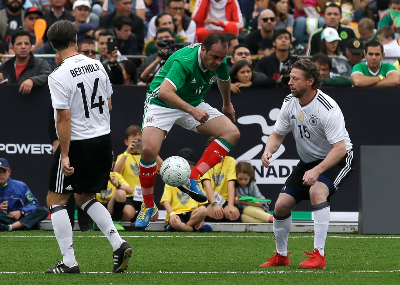 Mexico's Cuauhtemoc Blanco plays the ball as Germany's Steffen Freund, right, and Thomas Berthold look on, during a pair of "revenge" matches between former pro players from the Mexican and German national soccer teams in the Zocalo, Mexico City's main square, Sunday, July 9, 2017. The matches pitted against each other former players primarily from the 1986 and 1998 World Cup teams. (AP Photo/Rebecca Blackwell)