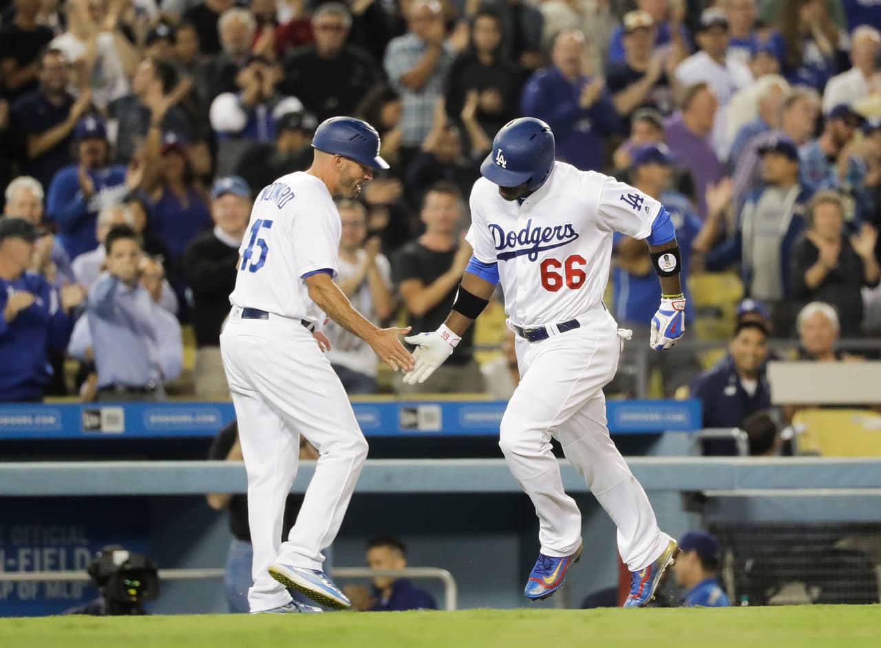 Yasiel Puig (derecha), de los Dodgers de Los Ángeles, celebra su jonrón con el coach de tercera base Chris Woodward en el sexto inning del juego contra los Diamondbacks de Arizona, el 7 de septiembre de 2016, en Los Angeles. (AP Foto/Jae C. Hong)