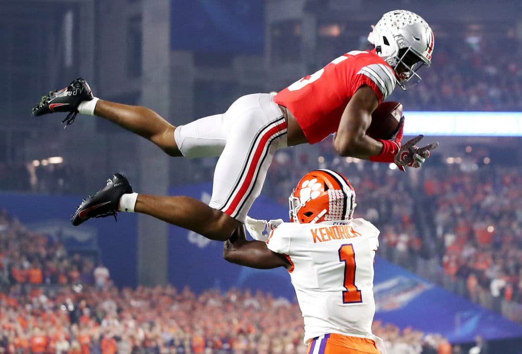 Garrett Wilson de los Ohio State Buckeyes es tacleado en el aire por Derion Kendrick de los Clemson Tigers.