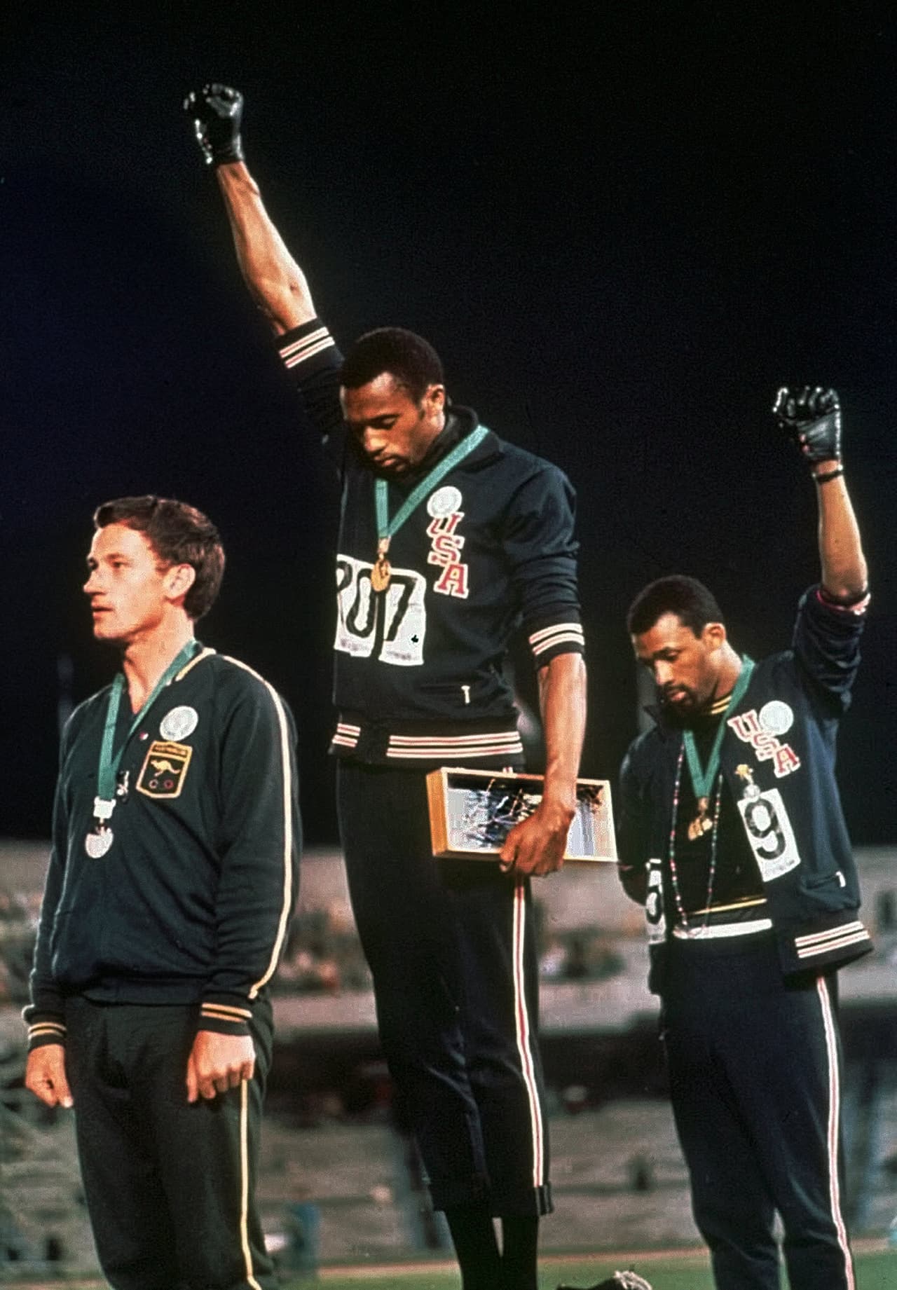 FILE - In this Oct. 16, 1968, file photo, extending gloved hands skyward in racial protest, U.S. athletes Tommie Smith, center, and John Carlos stare downward during the playing of "The Star-Spangled Banner" after Smith received the gold and Carlos the bronze medal in the 200 meter run at the Summer Olympic Games in Mexico City. Australian silver medalist Peter Norman is at left. San Francisco 49ers quarterback Colin Kaepernick's decision this week to refuse to stand during the playing of the national anthem as a way of protesting police killings of unarmed black men has drawn support and scorn far beyond sports. Through the years, "The Star-Spangled Banner" has become a symbol of both patriotism and politics. (AP Photo/FILE)