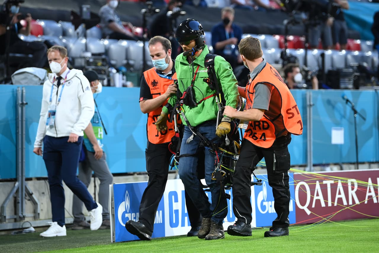MUNICH, GERMANY - JUNE 15: A greenpeace protester and pitch invader is removed from the pitch by stewards prior to the UEFA Euro 2020 Championship Group F match between France and Germany at Football Arena Munich on June 15, 2021 in Munich, Germany. (Photo by Matthias Hangst/Getty Images)