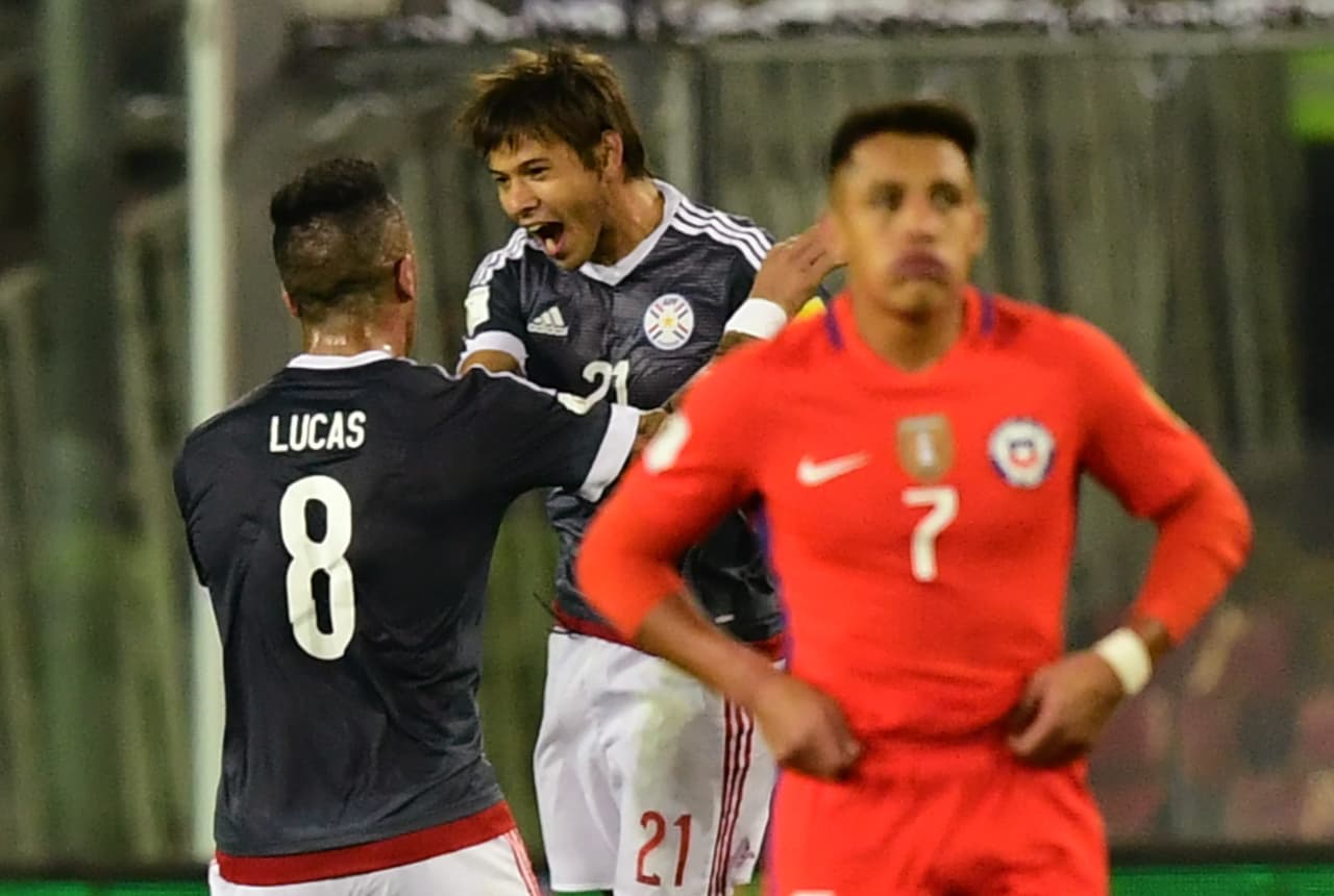 Paraguay's Lucas Barrios (L) and Oscar Romero celebrate after Chile's Arturo Vidal scored an own goal during their 2018 World Cup qualifier football match, in Santiago, on August 31, 2017. / AFP PHOTO / Martin BERNETTI (Photo credit should read MARTIN BERNETTI/AFP/Getty Images)