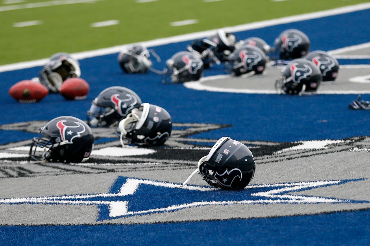 Several Houston Texans helmets sit over the Dallas Cowboys logo in the end zone as the Texans prepare for a morning work out at the Cowboys training facility, Monday, Aug. 28, 2017, in Frisco, Texas. The Texans are working out in the practice facility of the Cowboys because of floods pounding Houston. An exhibition game in the Texans' stadium Thursday might be moved to the home of the Cowboys.(AP Photo/Tony Gutierrez)