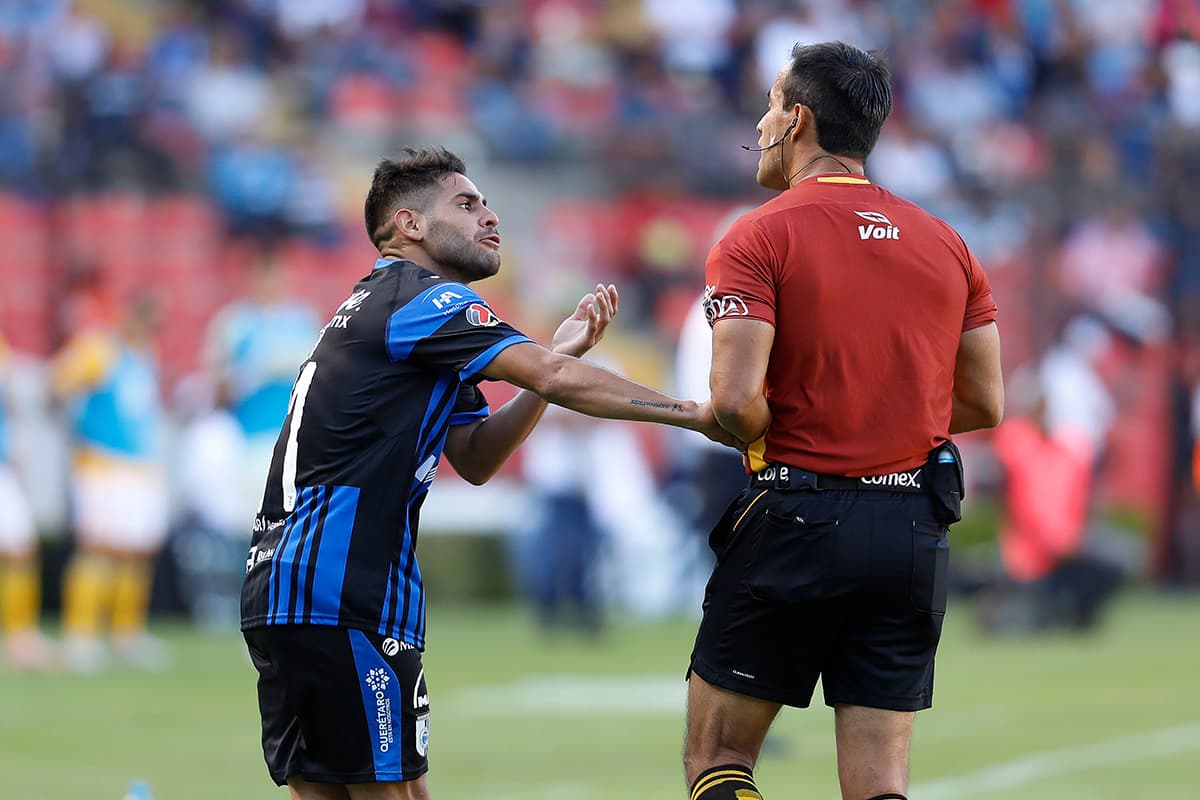 Daniel Villalva del Querétaro (izquierda) reclama al árbitro Jorge Isaac Rojas (derecha) durante el partido.
