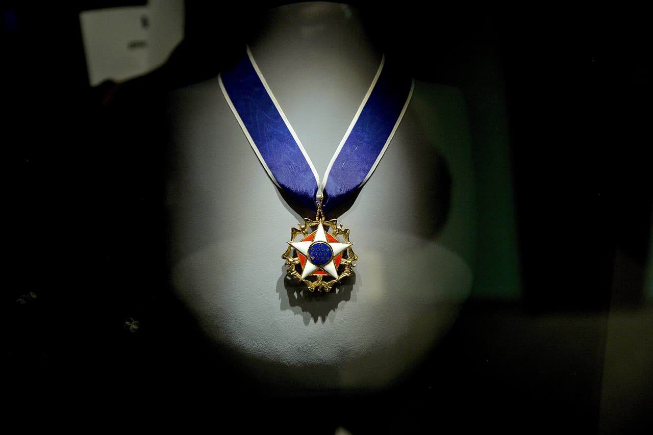 La medalla tiene forma de estrella, esmaltada en oro blanco, con un pentágono rojo detrás; el disco tiene 13 estrellas doradas sobre fondo azul, en su interior un anillo de oro. Águilas de Oro de América con alas de pie entre los puntos.