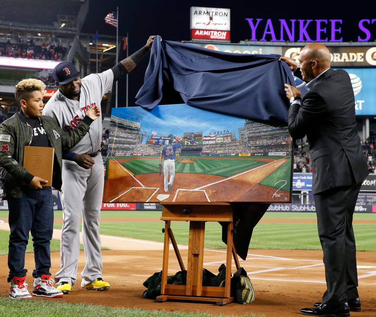 Boston Red Sox designated hitter David Ortiz, second from left, and his son D'Angelo, left, watch as retired New York Yankees relief pitcher Mariano Rivera helps unveil a painting that was given to Ortiz by the Yankees before a baseball game between the Yankees and the Red Sox in New York, Thursday, Sept. 29, 2016. (AP Photo/Kathy Willens)