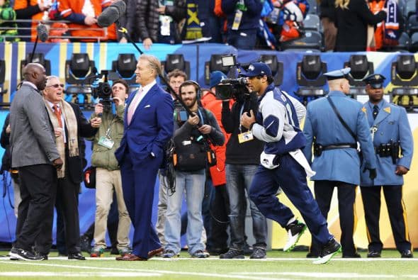 Russell Wilson en los calentamientos, al fondo se ve a John Elway.