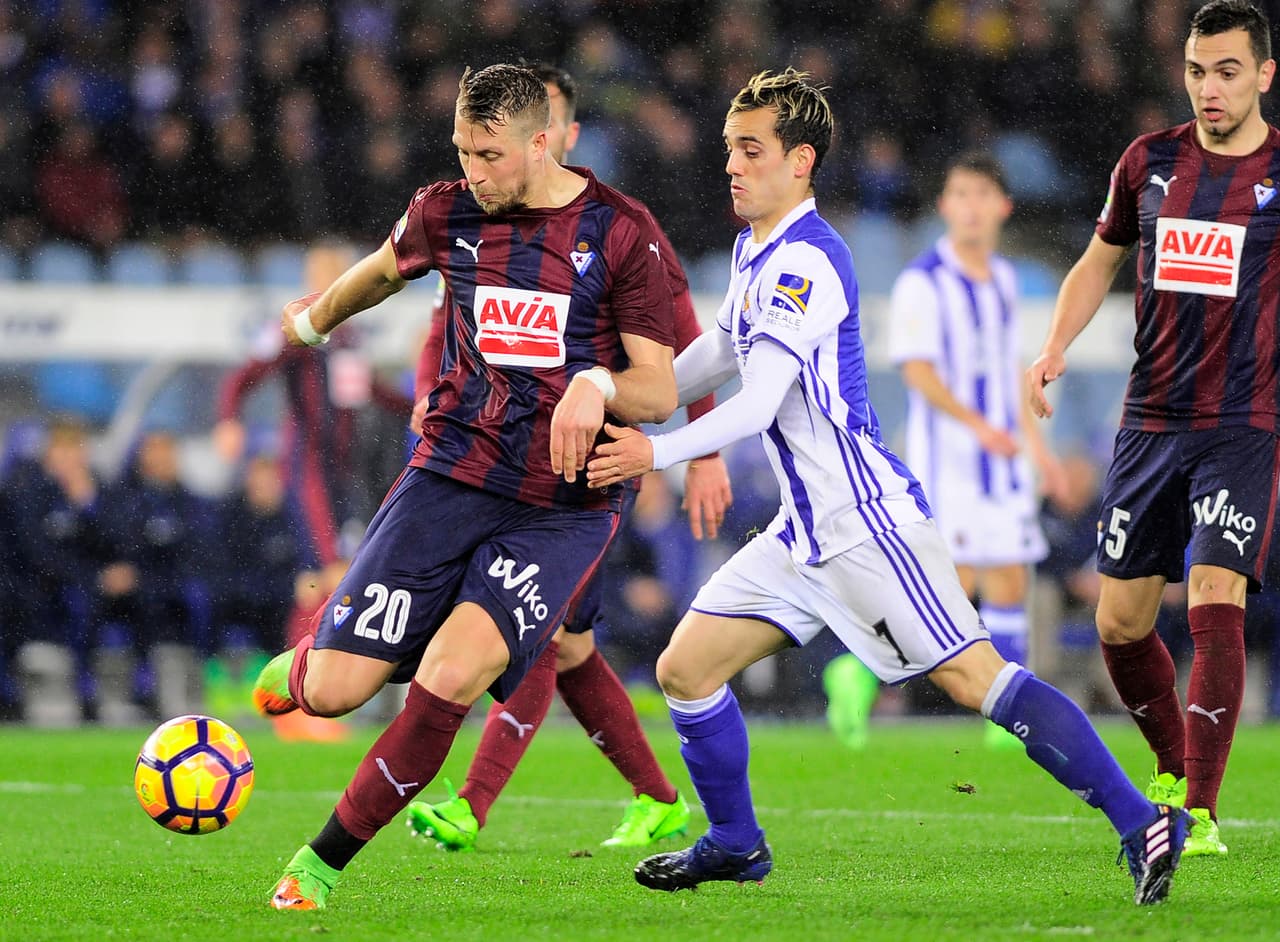 Juanmi (Real Sociedad) intenta evitar la salida de la defensa del Eibar por intermedio de Florian Lejeune.