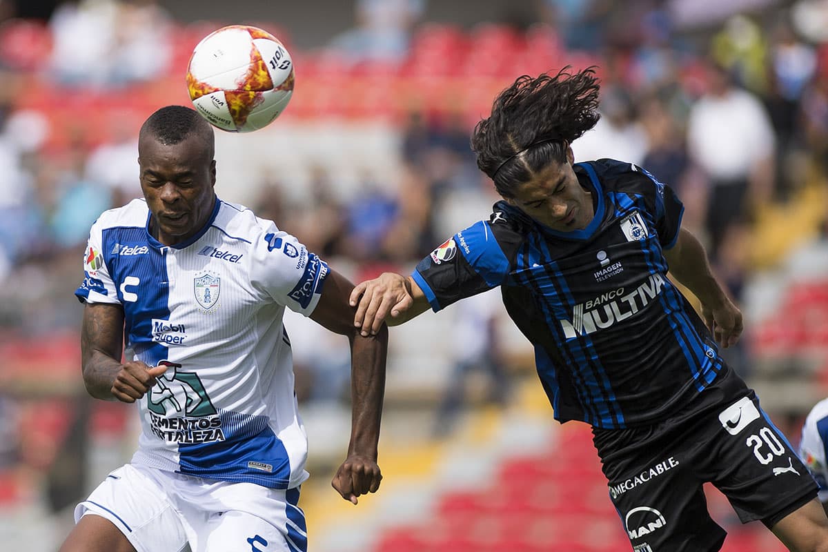 Duelo de fútbol aéreo entre el delantero Matías Britos del Querétaro (derecha) y el defensor colombiano del Pachuca Jaine Barreiro (izquierda).