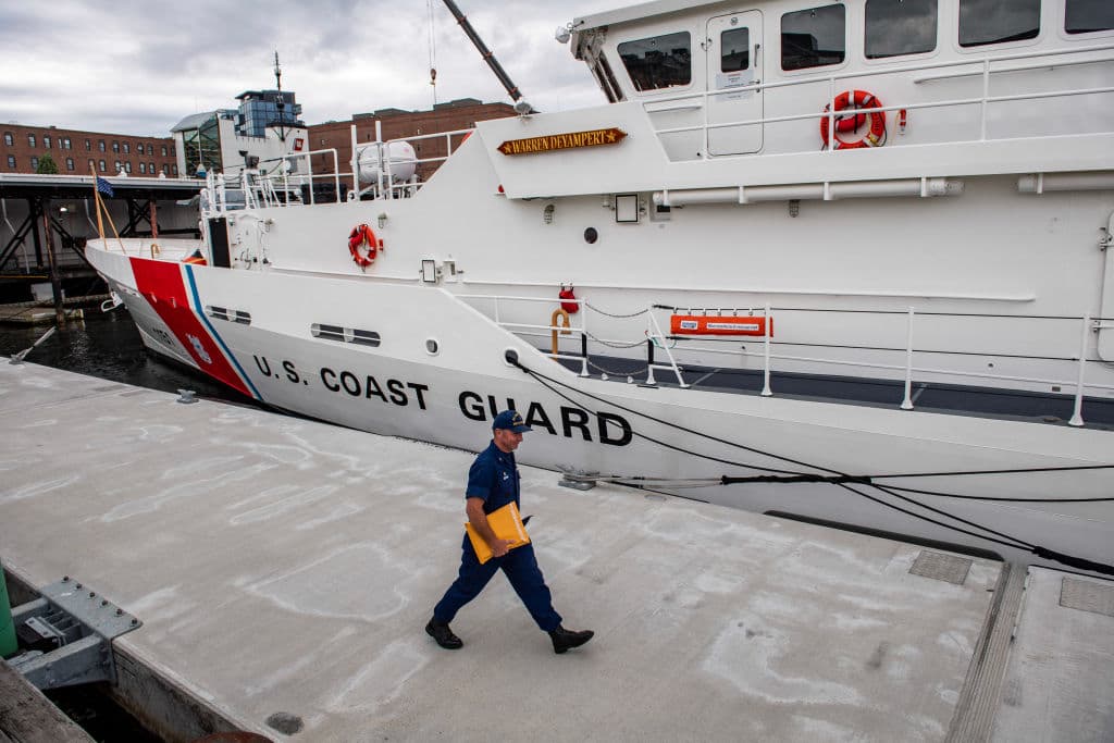 Un miembro de la Guardia Costera camina frente a uno de los cutter del cuerpo en Boston, Massachusetts.