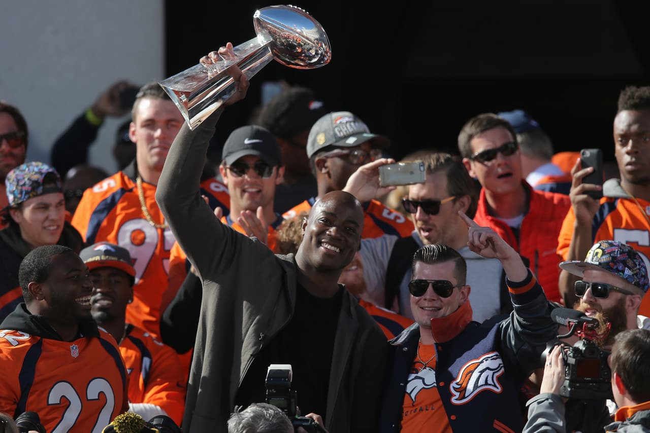 DENVER, CO - FEBRUARY 09: DeMarcus Ware (C) of the Denver Broncos hoists the Lombardi Trophy along with C.J. Anderson (L) of the Denver Broncos and John Bowlen (R), son of Pat Bowlen the Owner and CEO of the Denver Broncos as the Super Bowl 50 Champion Denver Broncos are honored at a rally on steps of the Denver City and County Building on February 9, 2016 in Denver, Colorado. The Broncos defeated the Carolina Panthers 24-10 in Super Bowl 50. (Photo by Doug Pensinger/Getty Images)