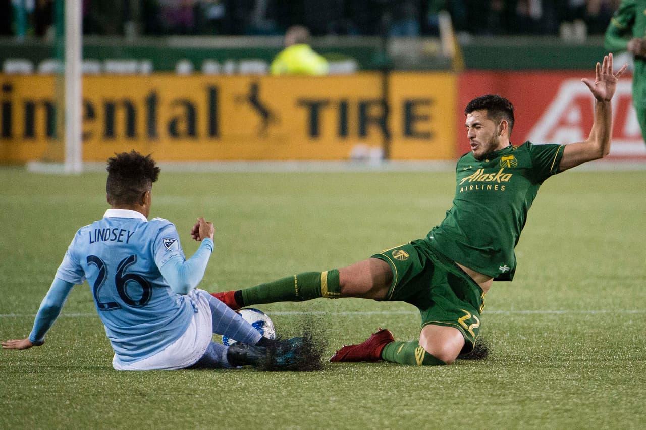 Jun 9, 2018; Portland, OR, USA; Sporting Kansas City defender Jaylin Lindsey (26) and Portland Timbers midfielder Cristhian Paredes (22) slide for possession of the ball during the second half at Providence Park. The game ended tied 0-0. Mandatory Credit: Troy Wayrynen-USA TODAY Sports