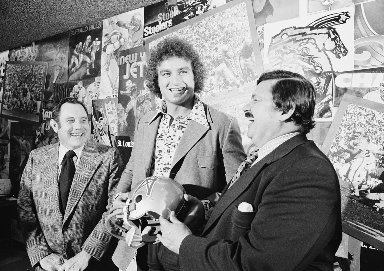 1973 JOHN MATUSZAK | DE Tampa Bay - 
<b>Houston Oilers</b>
<br>
<br>John Matuszak fue elegido como el primer jugador seleccionado en el draft, se encuentra con sus nuevos jefes por primera vez en una conferencia de prensa el 30 de enero de 1973. A su izquierda el entrenador principal de los Houston Oilers, Bill Peterson, y a la derecha el propietario del equipo, KS ‘Bud’ Adams.