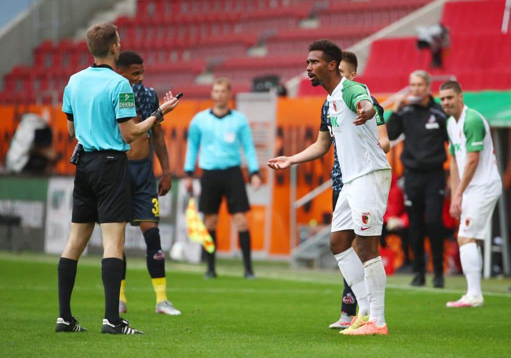 Benjamin Cortus, árbitro del encuentro, dialoga con Noah Sarenren Bazee del Augsburg durante el partido.