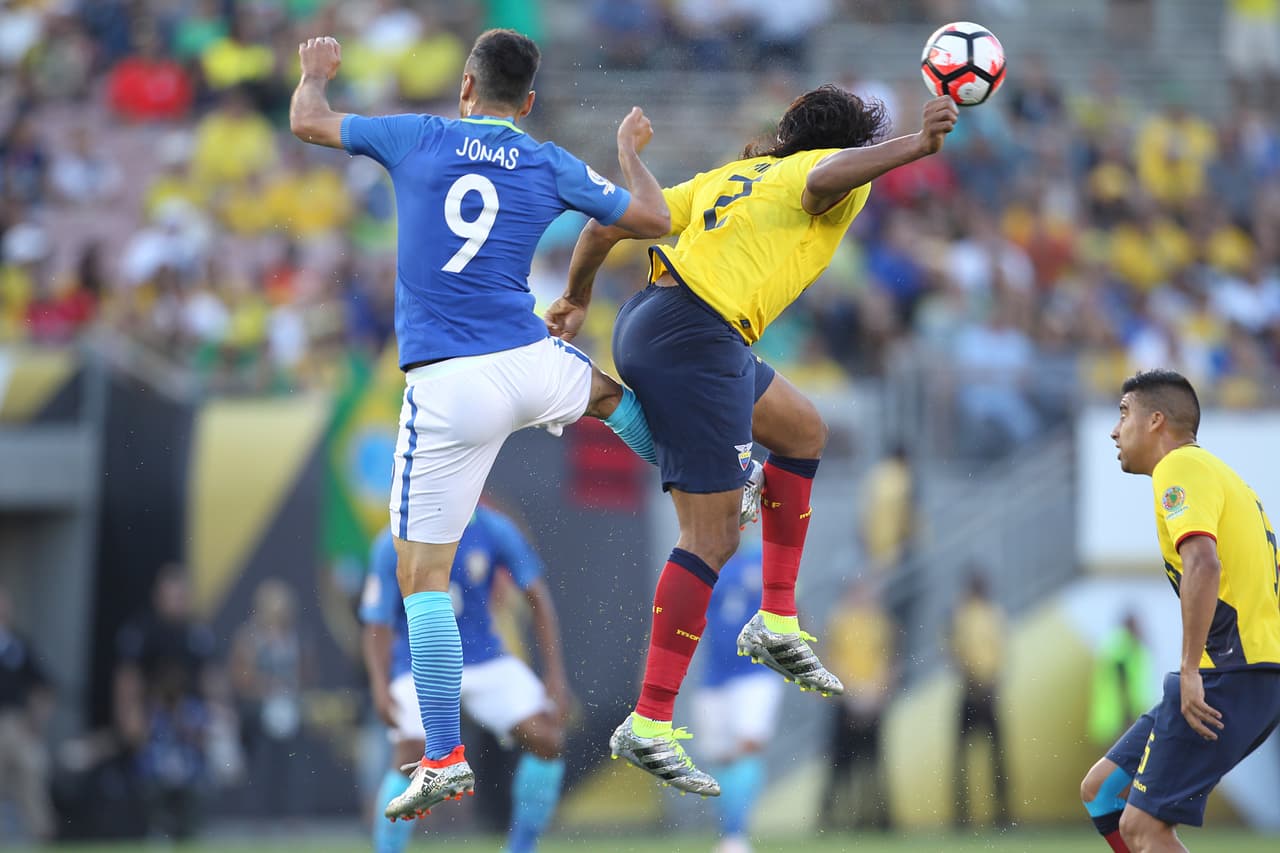 Jonas de Brasil salta por el balón con Arturo Mina de Perú.