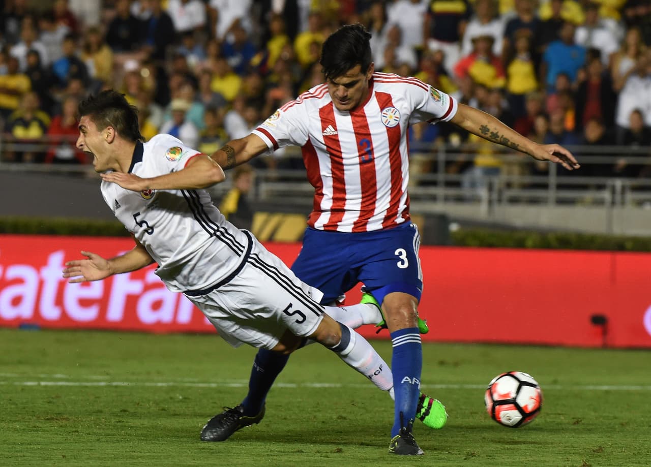 Gustavo Gómez, de Paraguay, y Guillermo Celis, de Colombia, luchan por la pelota.