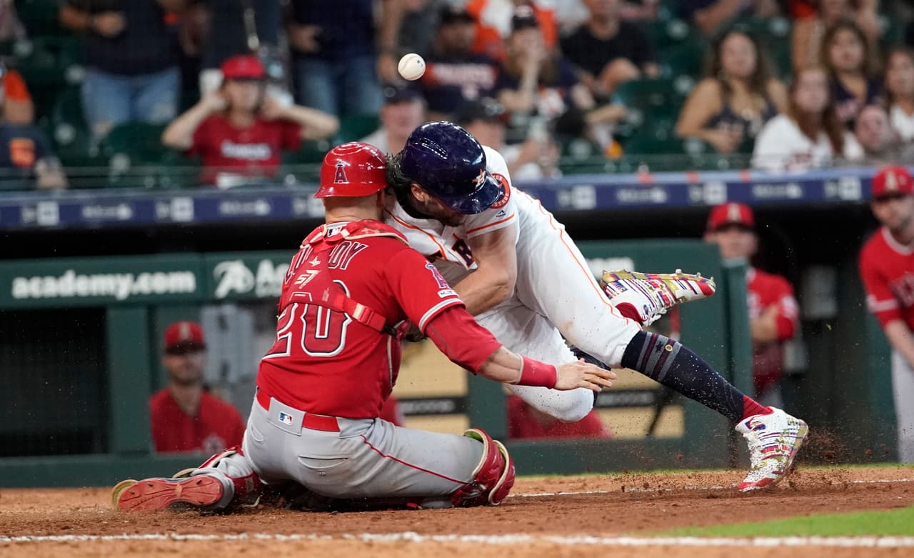 Jake Marisnick, de los Astros de Houston, a la derecha, choca con el catcher Jonathan Lucroy (20) de los Angelinos de Los Ángeles mientras intentaba anotar durante la octava entrada el domingo 7 de julio de 2019 en Houston. Marisnick fue llamado bajo la regla de colisión del plato de home.