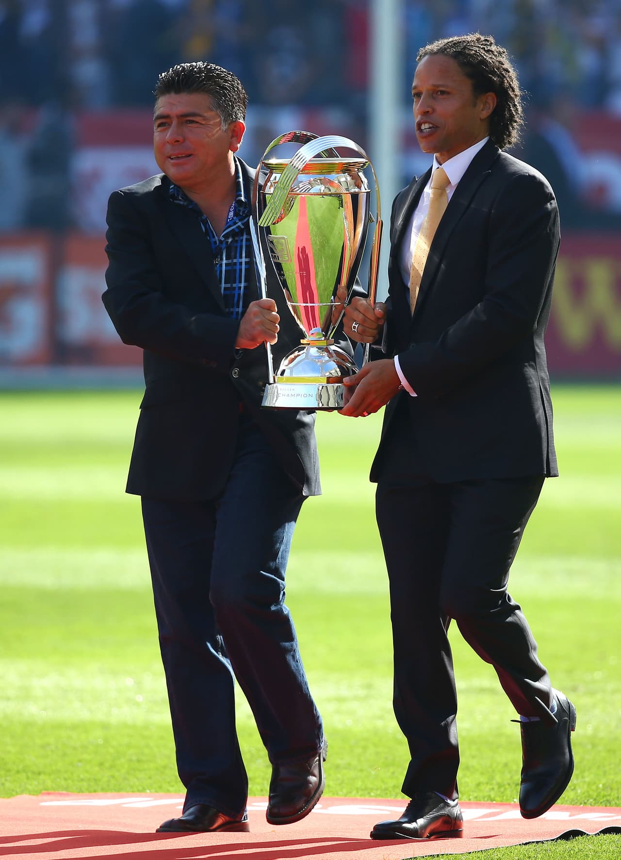 Mauricio Cienfuegos y Cobi Jones cargando el actual trofeo de la MLS Cup