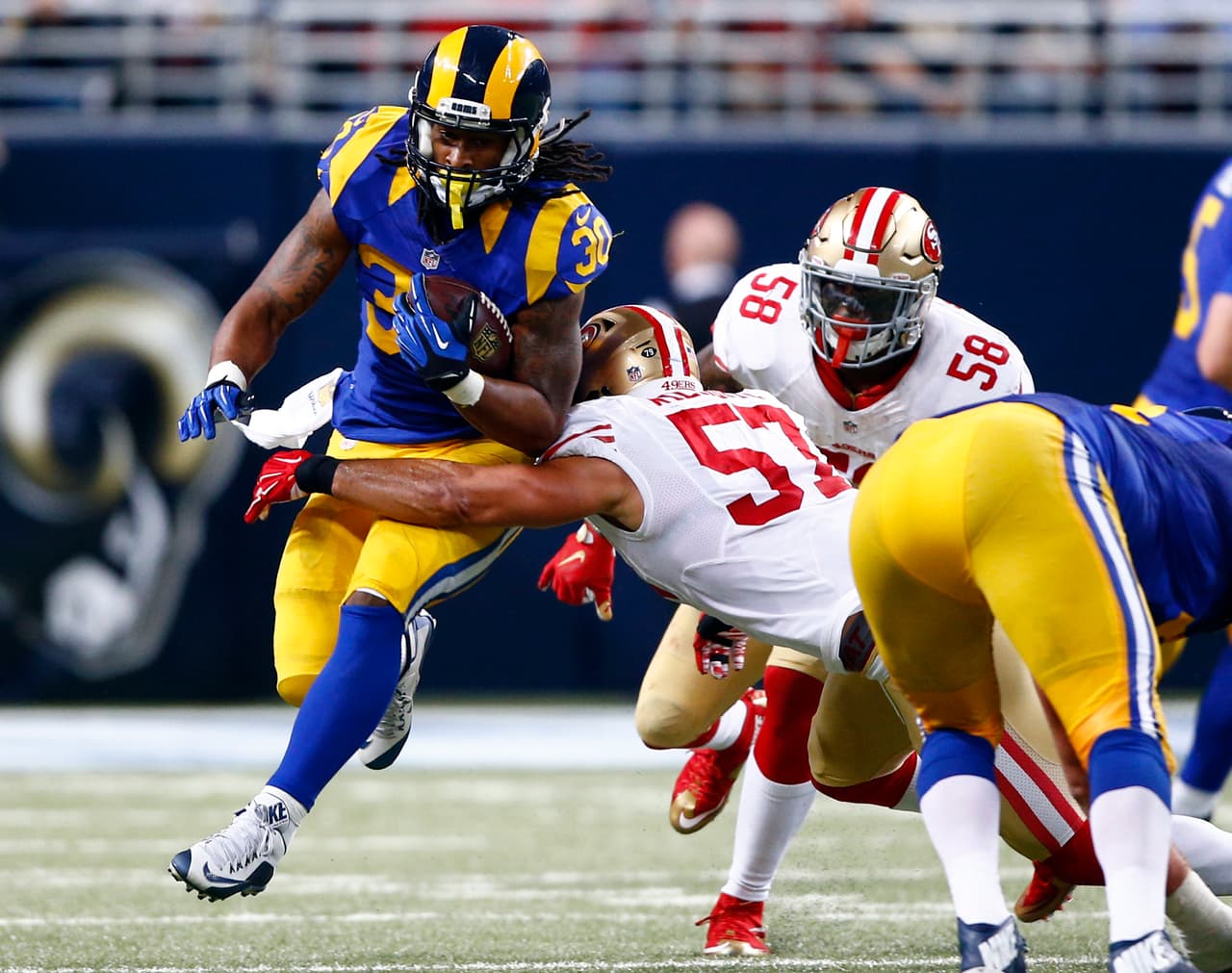 Todd Gurley, running back de los rams de San Luis, logra un primero y diez superando a los linebackers Michael Wilhoite y Eli Harold (58), de los 49ers de San Francisco, en el tercer cuarto del juego del domingo 1 de noviembre de 2015, en San Luis. (Foto AP/Billy Hurst)
