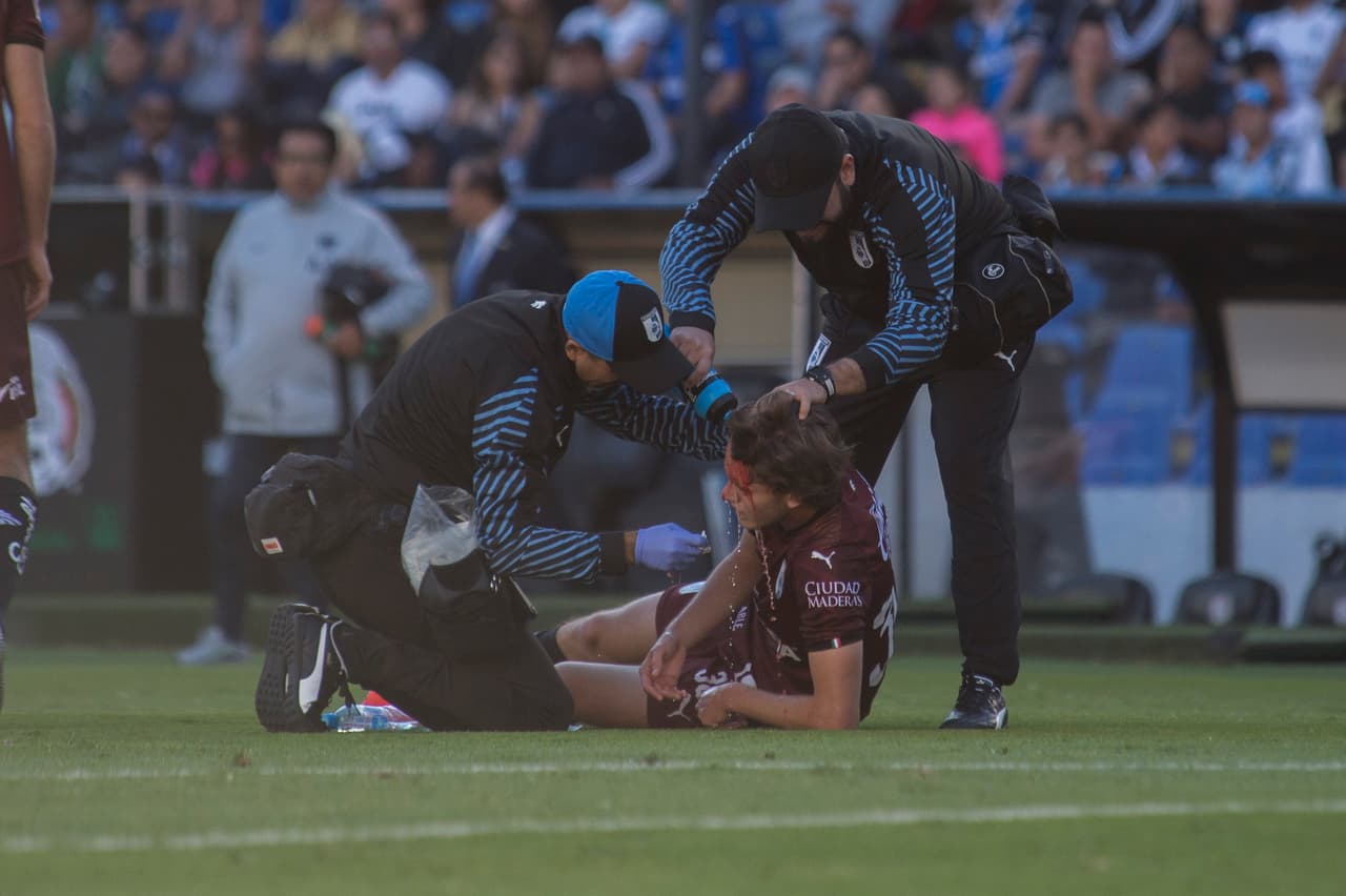 El mediocampista de los Gallos Marcel Ruiz (centro) resultó con una cortada en su cabeza tras chocar con un rival.