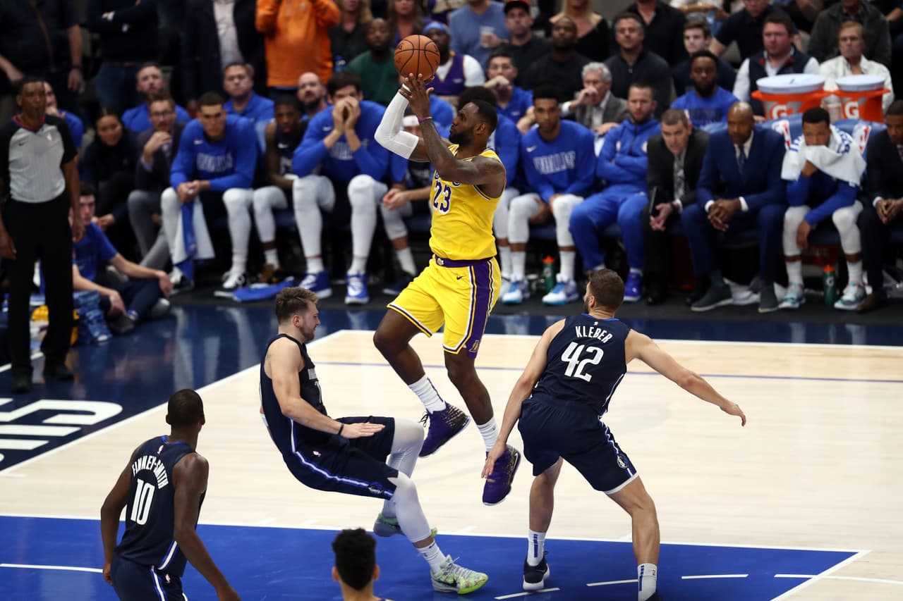 LeBron James anota mientras Luka Doncic cae al suelo.