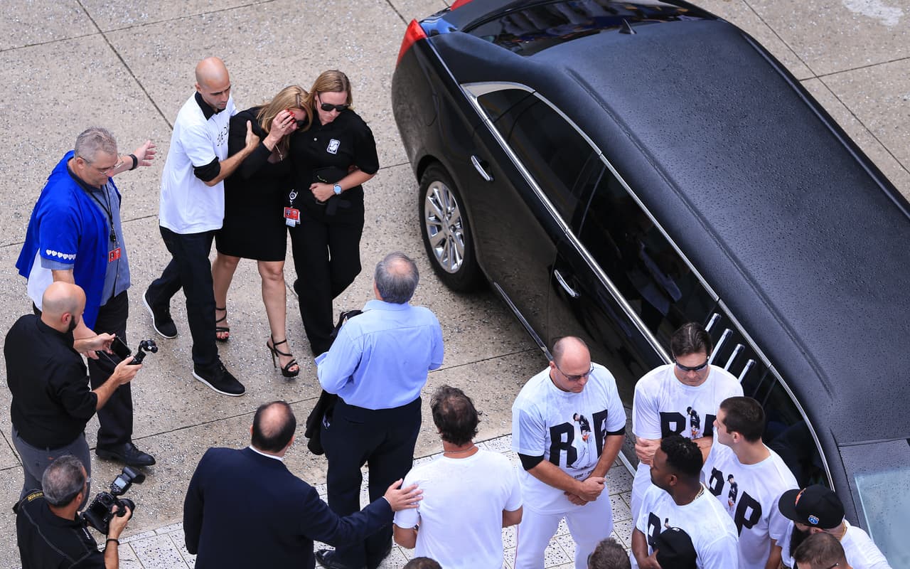 El dueño de los Miami Marlins, Jeffrey Loria, y el manager Don Mattingly, reciben a la madre que llegó cuando estaban en plena conmemoración.