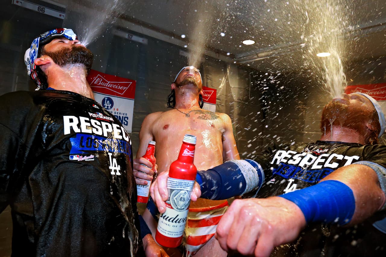 Adrián González (izq.), Josh Reddick (centro) y Justin Turner (der.) de los Dodgers de Los Angeles celebran en la sede del club después de ganar el quinto partido de la Serie Divisional de la Liga Nacional a los Nacionales de Washington, 4-3. Ahora, en la definición contra Cachorros por el paso a la Serie Mundial, van 1-1.