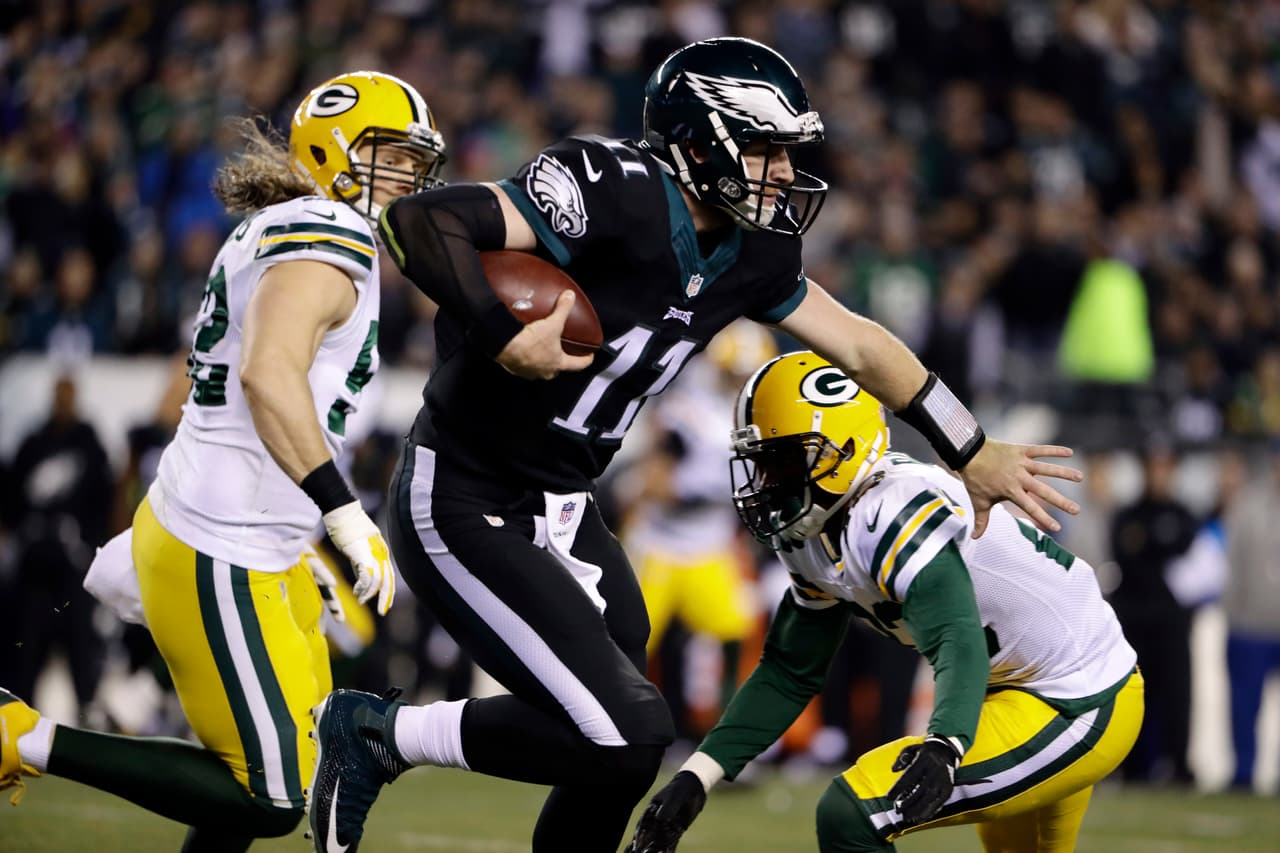 Philadelphia Eagles' Carson Wentz, center, scrambles past Green Bay Packers' Damarious Randall, right, and Clay Matthews during the first half of an NFL football game, Monday, Nov. 28, 2016, in Philadelphia. (AP Photo/Matt Rourke)