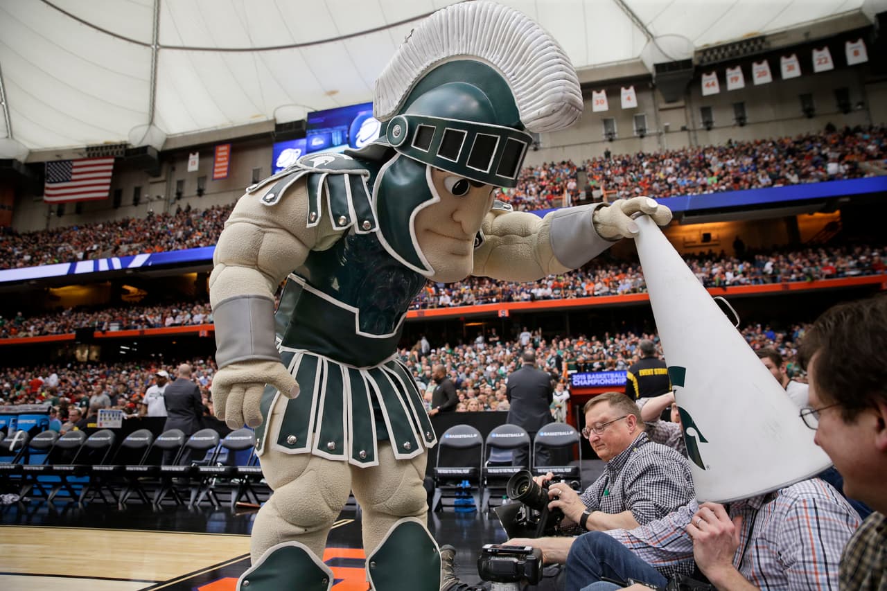 En ocasiones dan ganas de callar por un momento a ciertos periodistas. La mascota de Michigan State no pudo contenerse. No solo silenció, también cegó al fotógrafo ubicado en la línea de la duela.