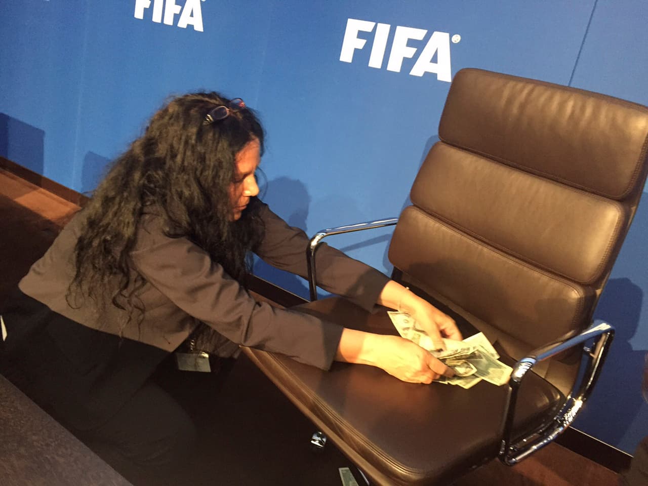 Una empleada de la FIFA recoge los billetes falsos que un comediante le arrojó a Sepp Blatter durante la conferencia de prensa del pasado 20 de julio en Zurich. Blatter postergó la reunión mientras limpiaban el lugar.