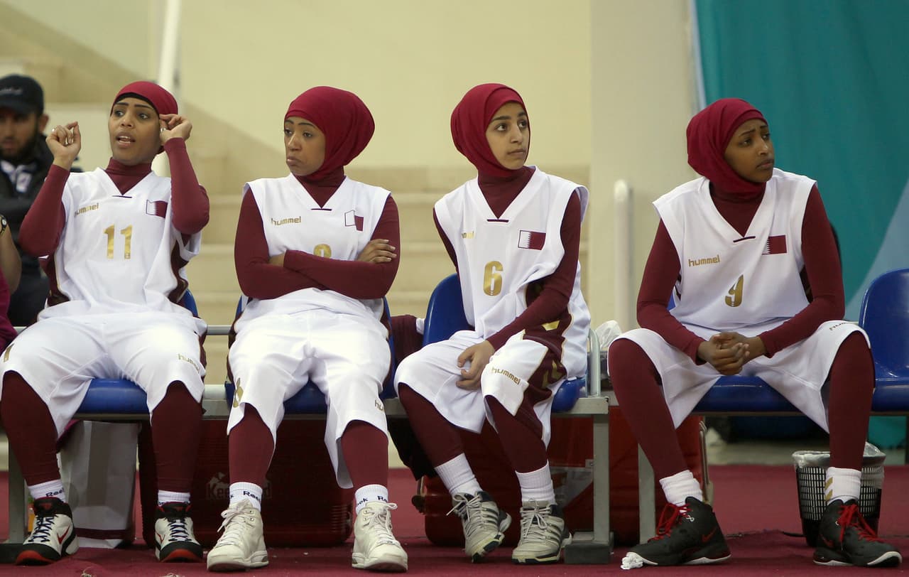 Qatari players wearing Islamic sportswear especially designed for women sit on the bench during their 2011 Arab Games basketball match against Lebanon in Doha on December 19, 2011. AFP PHOTO/MARWAN NAAMANI (Photo credit should read MARWAN NAAMANI/AFP/Getty Images)