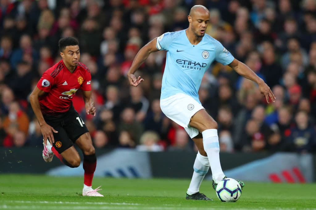Vincent Kompany de Manchester City protege el balón ante la presión de Jesse Lingard del Manchester United en los primeros minutos.