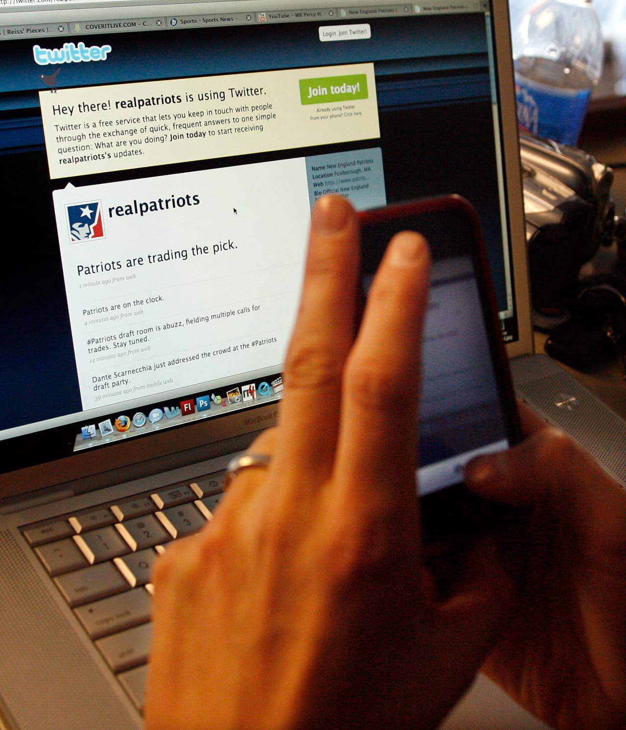 A reporter takes a photo of his computer screen with his cell phone after learning through realpatriots twitter feed, that the New England Patriots traded their 23rd pick in the 2009 NFL Draft to Baltimore for a 25th pick, at Gillette Stadium in Foxborough, Mass., Saturday, April 25, 2009. (AP Photo/Stew Milne)