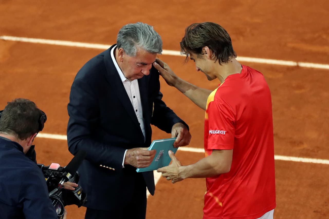 David Ferrer (d) recibe un obsequio del extenista Manolo Santana, a la finalización del partido de segunda ronda del Mutua Madrid Open que ha disputado ante el alemán Alexander Zverev, último encuentro como profesional en la carrera del tenista alicantino, este miércoles en la Caja Mágica.
